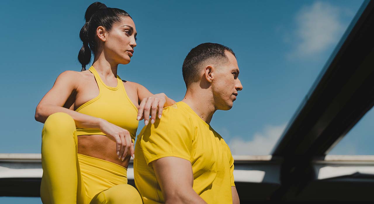 Holmes Place | γυναίκα και άντρα με κίτρινα αθλητικά ρούχα σε εξωτερικό χώρο του γυμναστηρίου